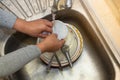 TheÃ¢â¬â¹ Hand cleaning of female or housewife woman washing dishes with a yellow sponge in kitchen sink Royalty Free Stock Photo